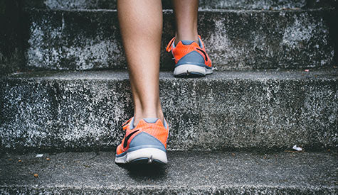 Benen met sportschoenen die stenen trap oplopen